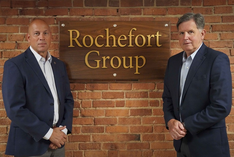 Two men standing in front of a sign that says Rochefort Group