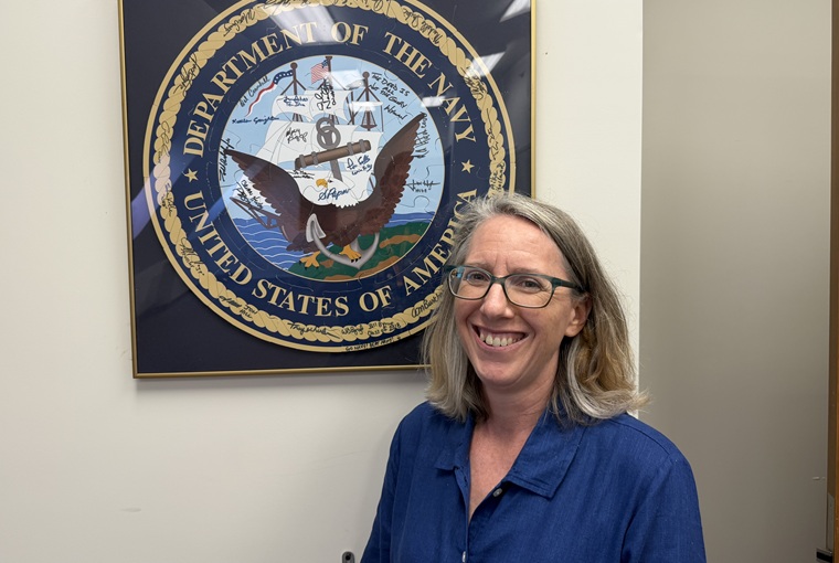 A woman in front of the Navy logo