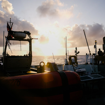 Crewmembers aboard the Coast Guard Cutter Bertholf (WMSL 750) watch as the sun rises over the stern of the cutter, which is patrolling in the Western Pacific Ocean, Feb. 21, 2024. The Western Pacific mission includes partnerships with several Asian nations to improve interoperability between coast guards and navies. U.S. Coast Guard photo by Chief Petty Officer Oliver Fernander