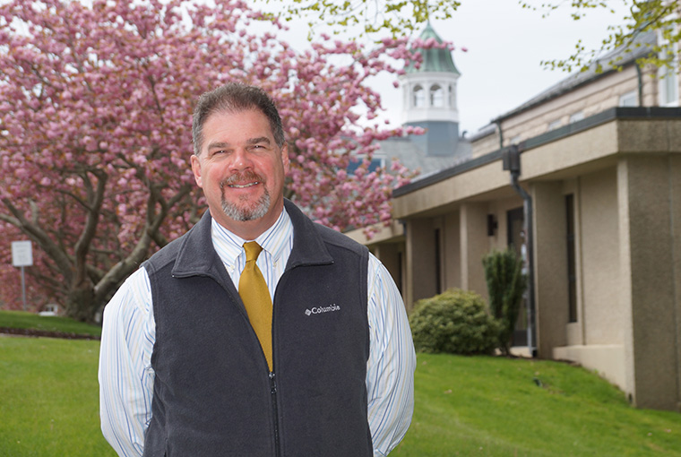 Photo of Professor William Nault with the college in the background.