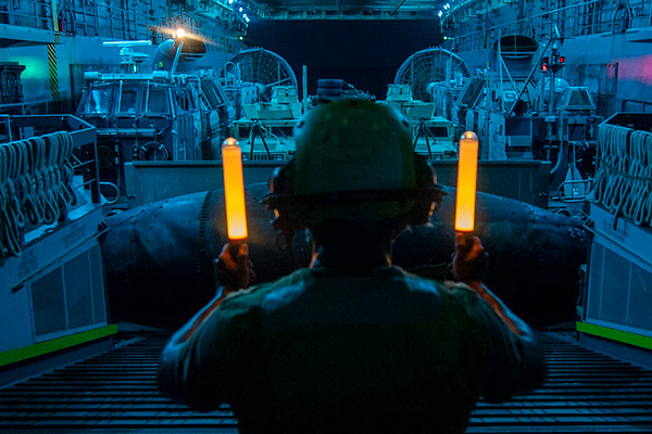 Seaman Juan Rivera signals the Landing Craft, Air Cushion 57 pilot, assigned to Assault Craft Unit 5, during well deck operations aboard the amphibious transport dock ship USS John P. Murtha (LPD 26).