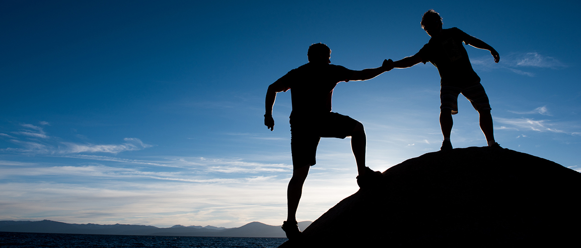 People helping each other climb a mountain